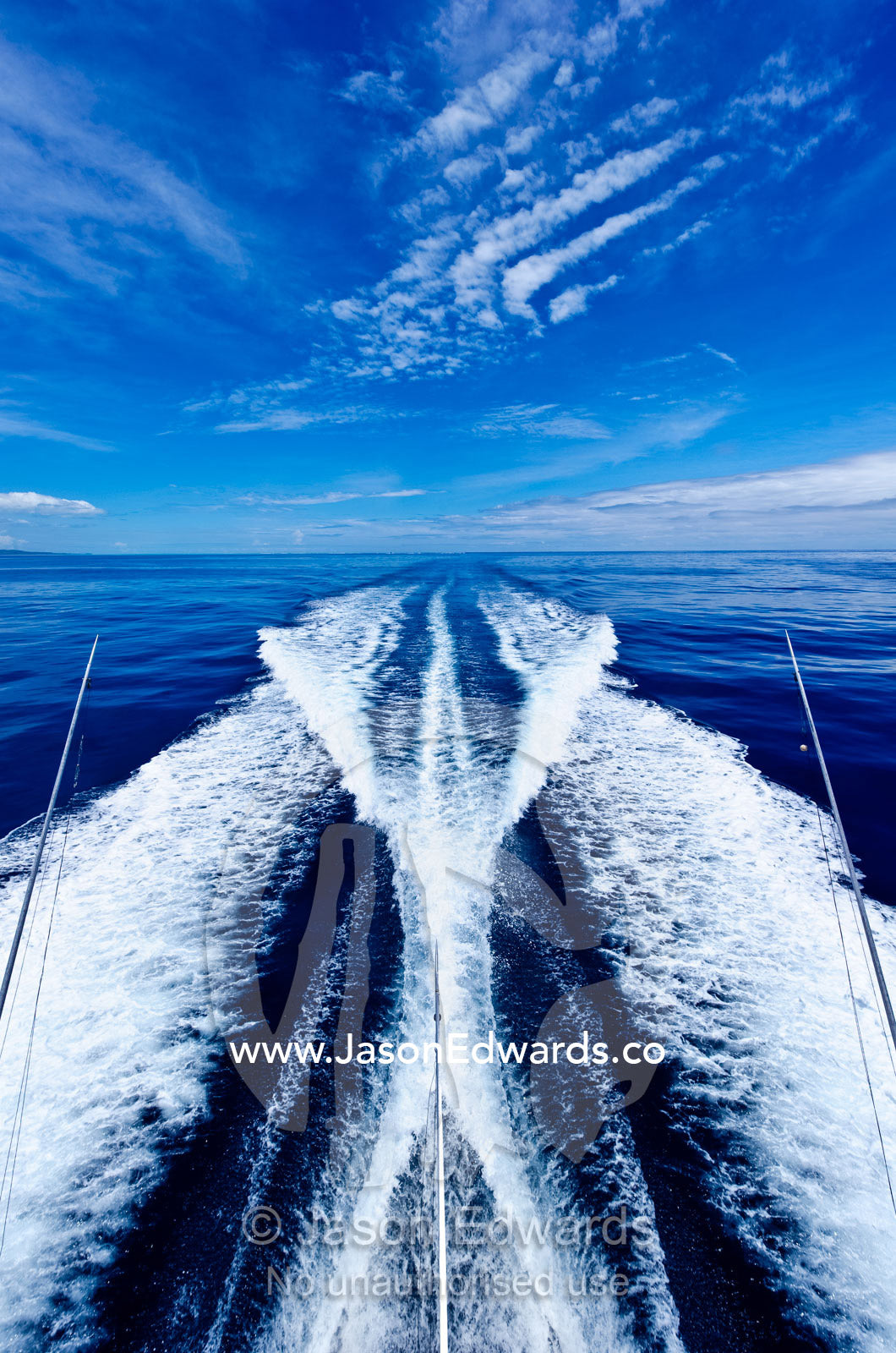 The wake of a luxury boat plowing through a calm turquoise ocean. Nanuya Balavu Island, Yasawa Group, Pacific Ocean, Fiji Islands.