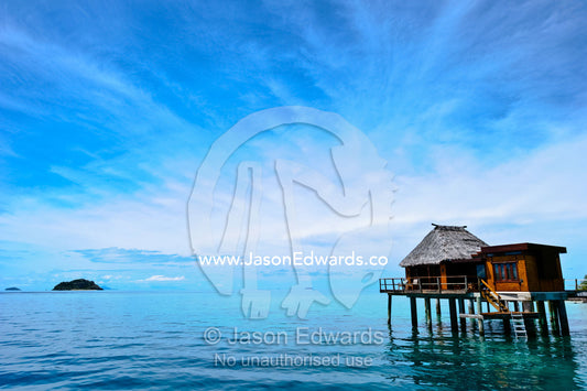 An exclusive resort bungalow over a calm tropical sea. Likuliku Lagoon Resort, Malolo Island, Mamanuca Islands, Pacific Ocean, Fiji Islands.