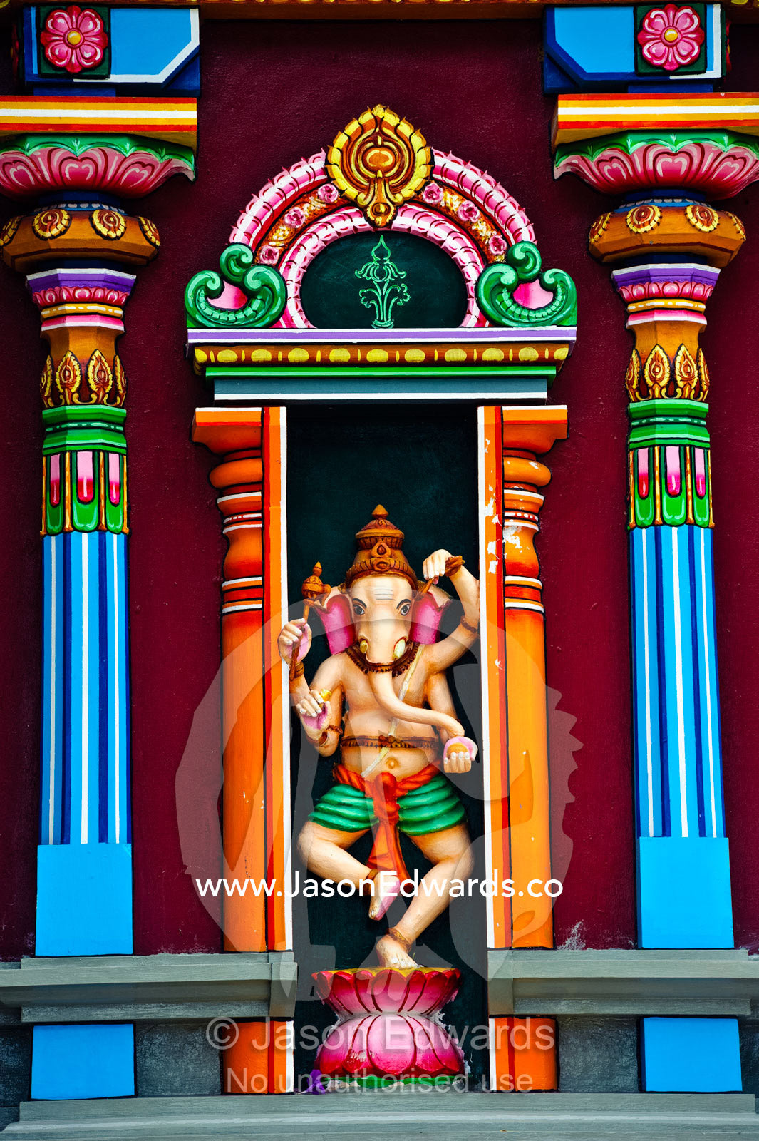 A colorful statue of Ganesh standing between pillars on a temple wall. Sri Siva Subramaniya Swami Temple, Nadi, Viti Levu Island, Pacific Ocean, Fiji Islands.