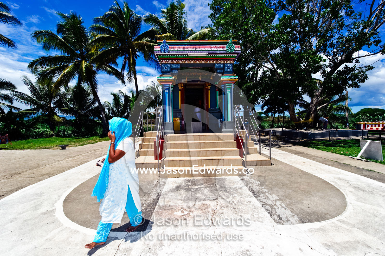 A woman in light blue returns from offering prayers at a Hindu temple. Sri Siva Subramaniya Swami Temple, Nadi, Pacific Ocean, Viti Levu Island, Fiji Islands.