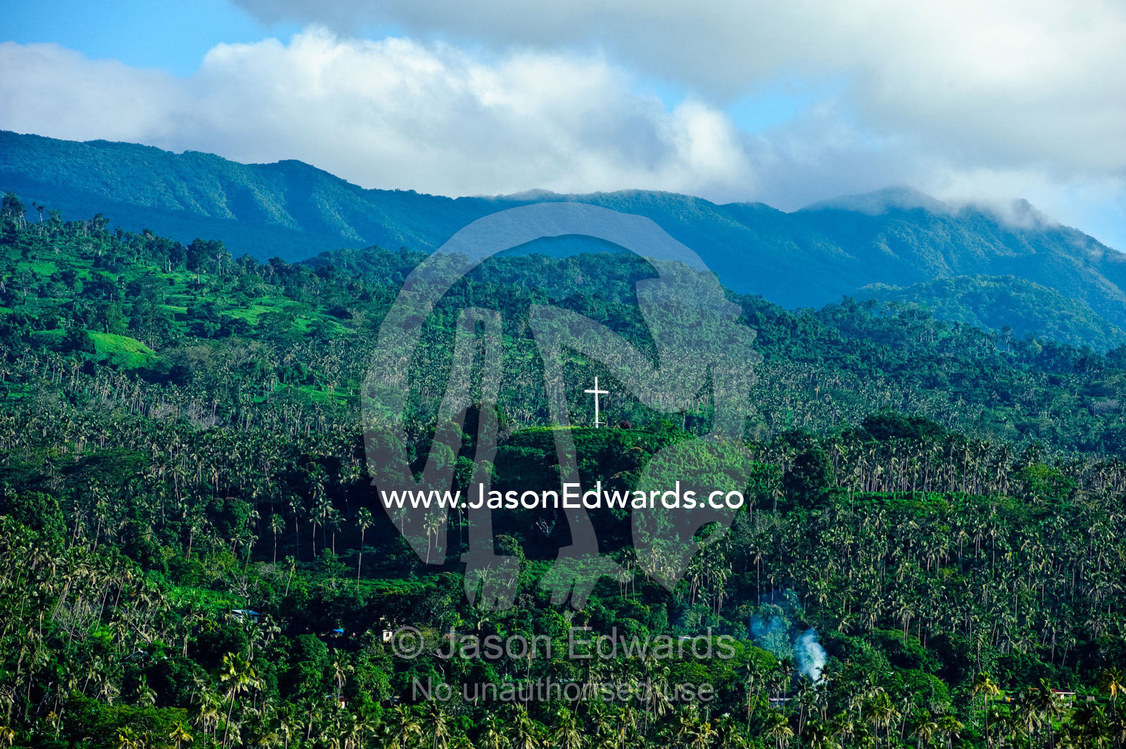 A crucifix on a lush hillside surrounded by palm tree plantations. Taveuni Island, Pacific Ocean, Fiji Islands.