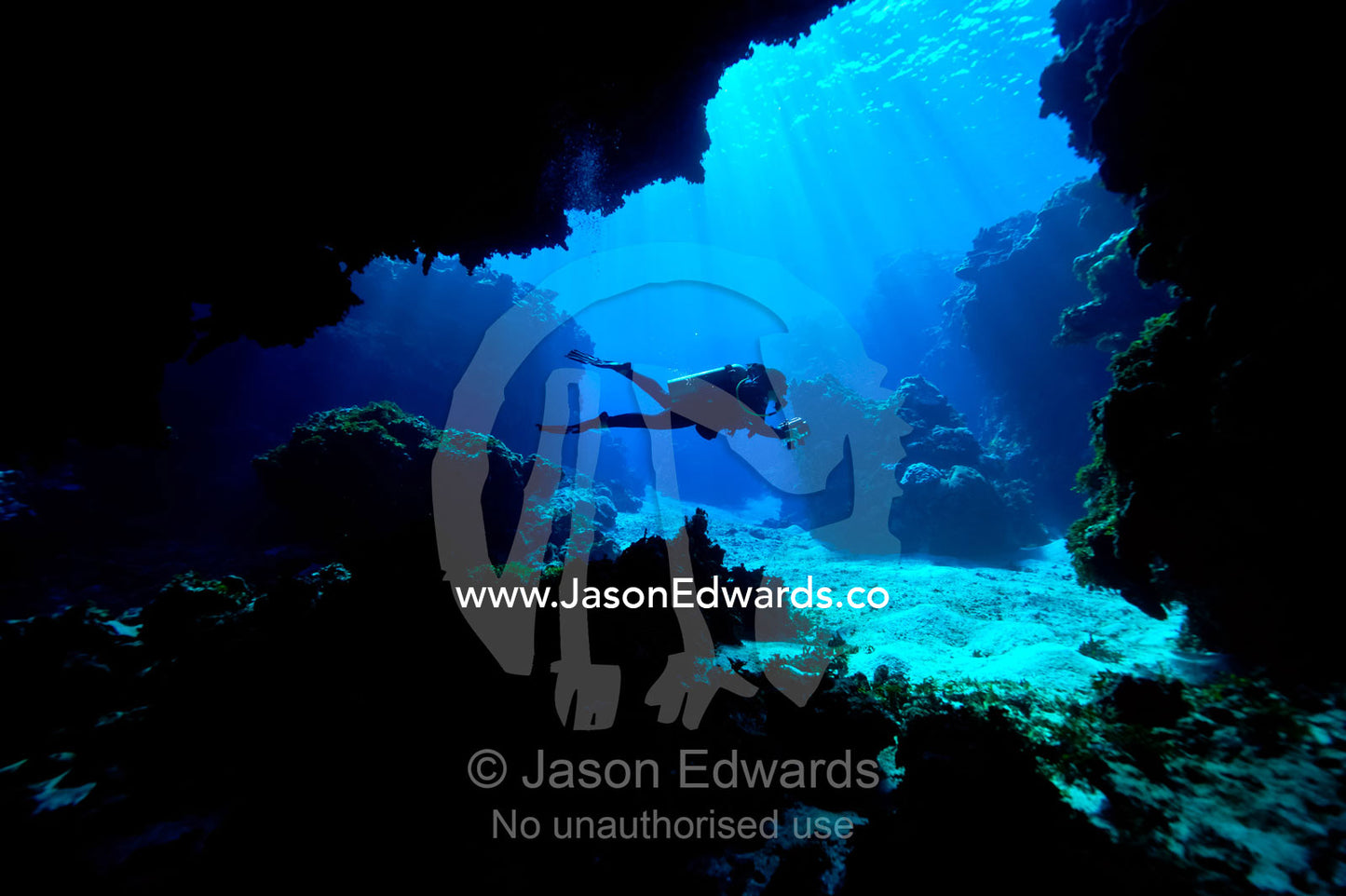A scuba diver exploring an underwater cave in a tropical coral reef. Kokod Point, Ringgold Isles Archipelago, Pacific Ocean, Fiji Islands.