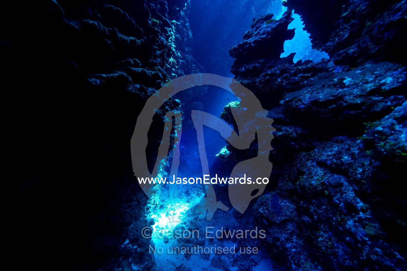 An underwater cave leads to a sunlit canyon between coral reefs. Kokod Point, Ringgold Atolls, Pacific Ocean, Fiji Islands.