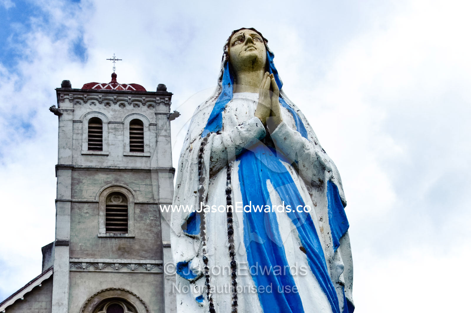 A statue of the Virgin Mary looks skyward in prayer before a church. Holy Cross Temple, Wairiki, Taveuni Island, Pacific Ocean, Fiji Islands.