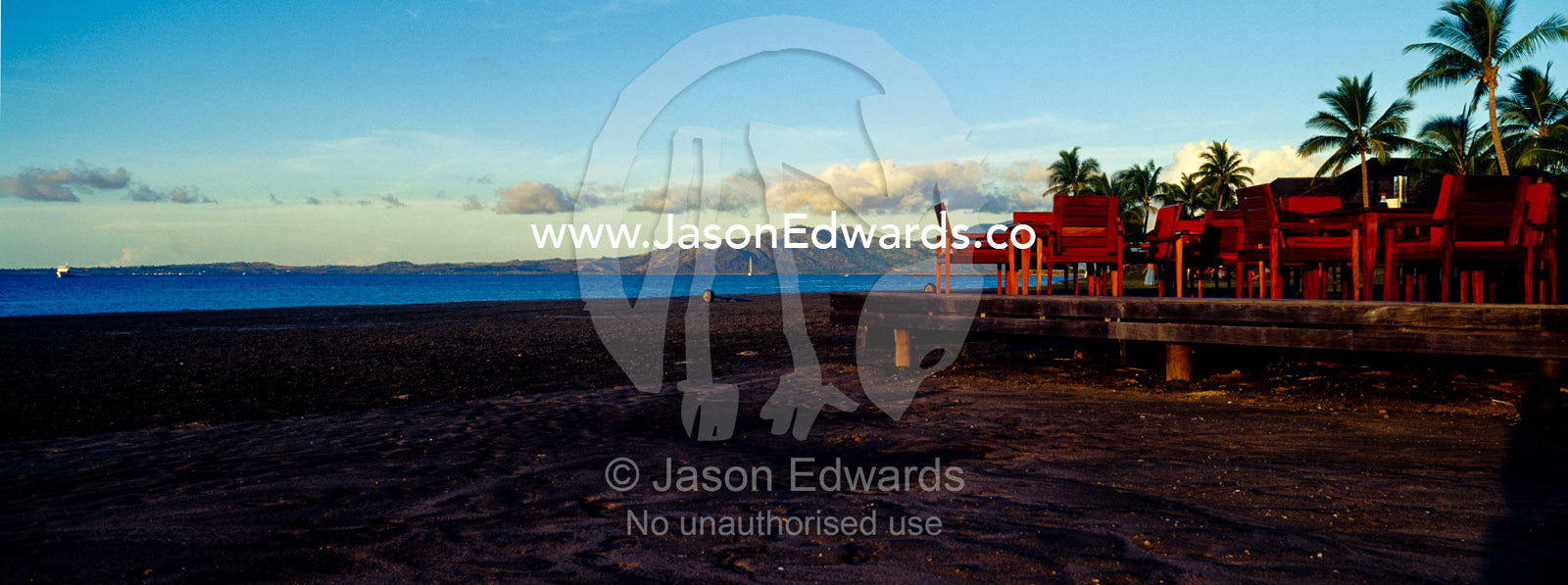 Deck chairs and dining tables overlooking the ocean at sunset. Viti Levu, Pacific Ocean, Fiji Islands.