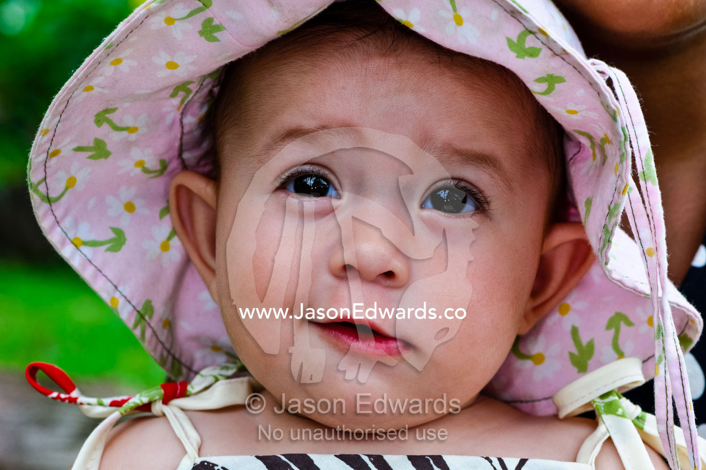 A smiling baby wearing a pink flowery summer hat to shade her face. Taveuni Island, Pacific Ocean, Fiji Islands.