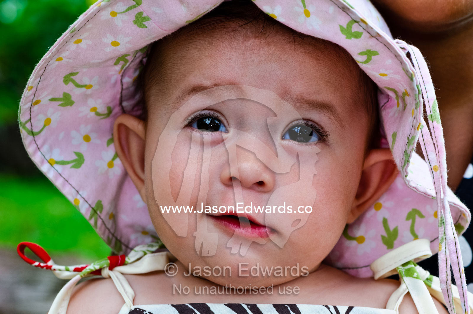 A smiling baby wearing a pink flowery summer hat to shade her face. Taveuni Island, Pacific Ocean, Fiji Islands.