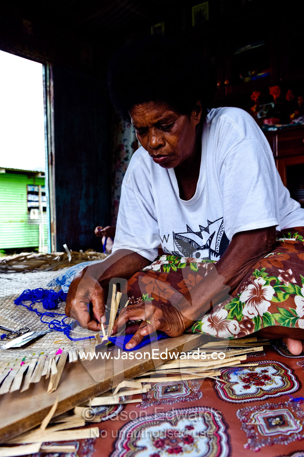 A lady hand-weaving a mat from banana leaves to go on the floor. Waitabu Marine Park, Taveuni Island, Pacific Ocean, Fiji Islands.