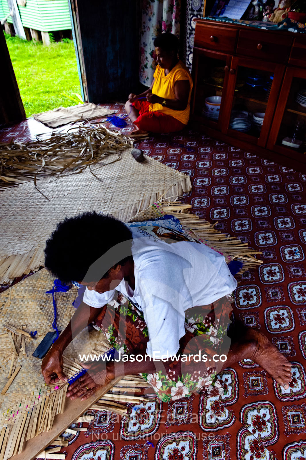 A woman hand-weaving a mat from banana leaves to go on the floor. Waitabu Marine Park, Taveuni Island, Pacific Ocean, Fiji Islands.