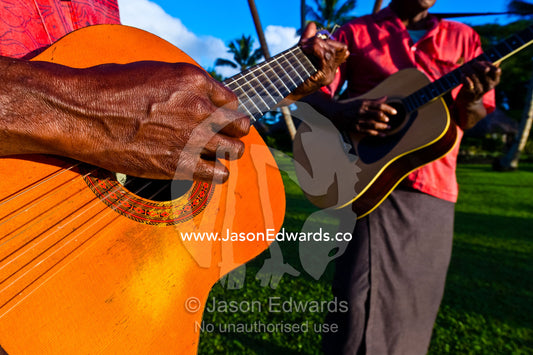 Musicians play acoustic guitars on a tropical island at sunset. Paradise Taveuni, Taveuni Island, Pacific Ocean, Fiji Islands.