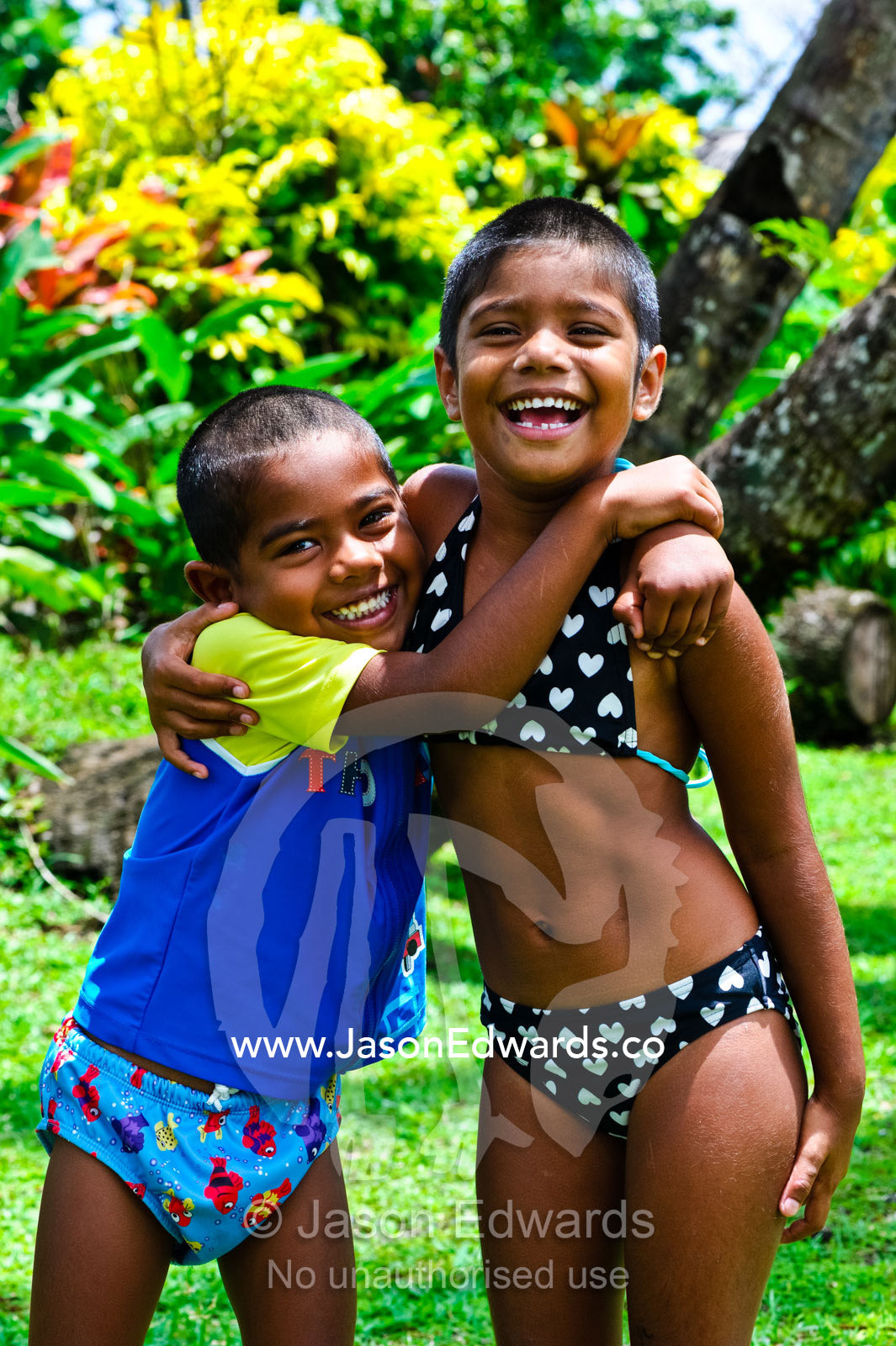 A brother and sister laughing and playing in a tropical garden. Paradise Taveuni, Taveuni Island, Pacific Ocean, Fiji Islands.