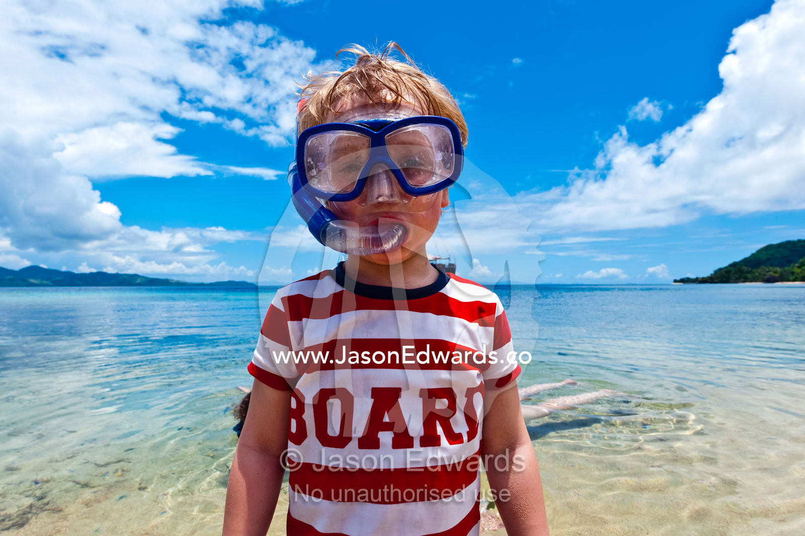 A boy wears his snorkel and mask in the shallows of a tropical island. Rabi Island, Somosomo Strait, Pacific Ocean, Fiji Islands.