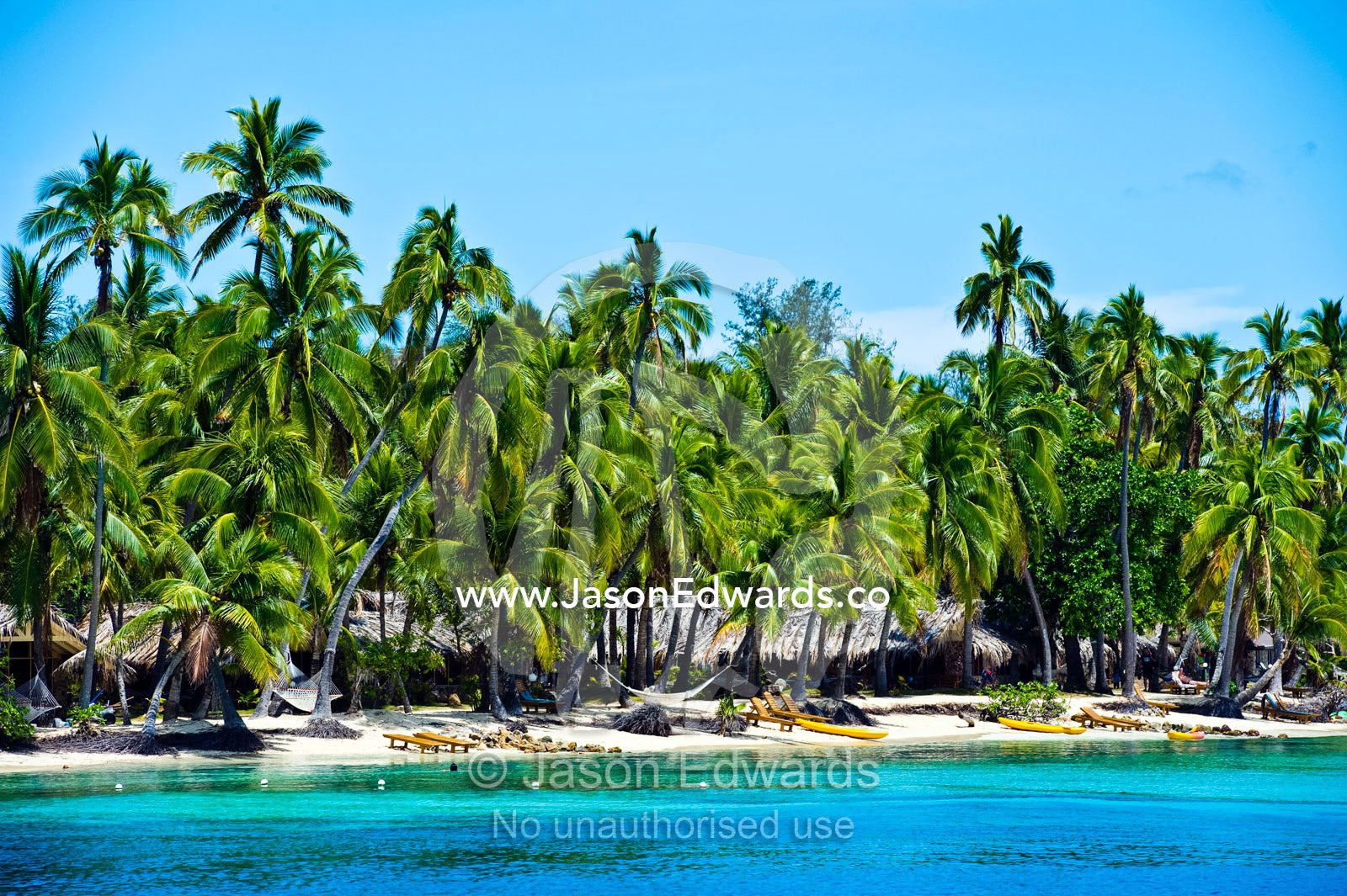 Lounge chairs and sea kayaks on the beach at a tropical island resort. Momi Bay, Malolo Archipelago, Pacific Ocean, Fiji Islands.
