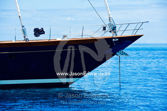 The bow of a luxury yacht anchored in a clear blue calm lagoon. Momi Bay, Viti Levu, Malolo Archipelago, Pacific Ocean, Fiji Islands.