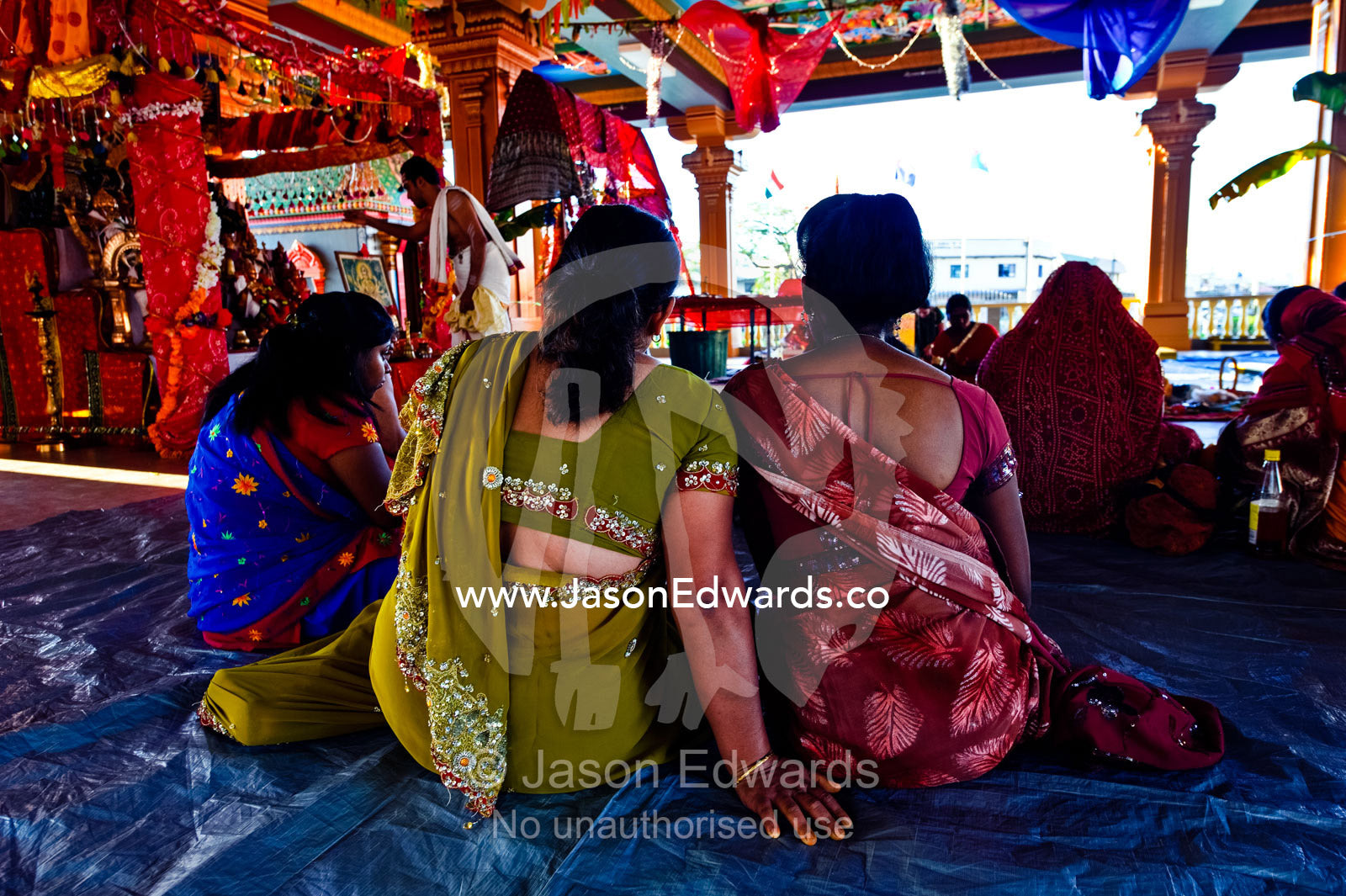 Women observe a priest offer prayers to the gods in a Hindu temple. Sri Siva Subramaniya Swami Temple, Nadi, Pacific Ocean, Fiji Islands.