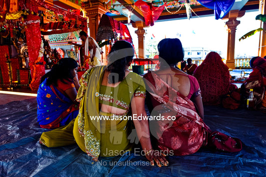 Women observe a priest offer prayers to the gods in a Hindu temple. Sri Siva Subramaniya Swami Temple, Nadi, Pacific Ocean, Fiji Islands.