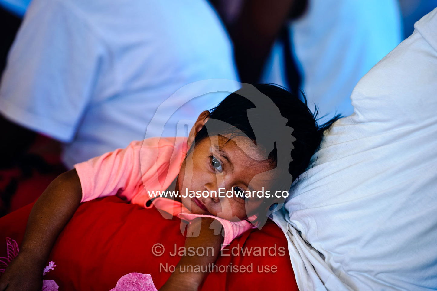 A small boy rests in his mother's lap during a village ceremony. Kioa Island, Somosomo Strait, Pacific Ocean, Fiji Islands.