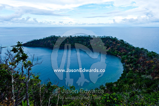 The forested slopes of an extinct volcano caldera rise from the ocean. Cobia Crater, Cobia Island, Ringgold Atolls, Pacific Ocean, Fiji Islands.