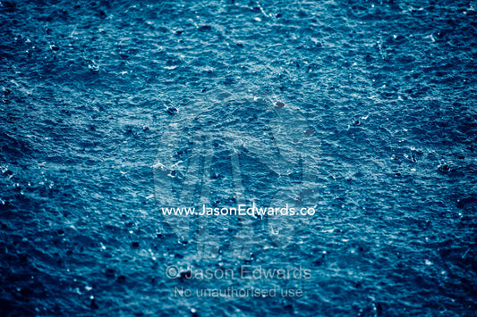 Torrential tropical downpours send raindrops into the ocean surface. Cobia Island, Ringgold Atolls, Pacific Ocean, Fiji Islands.