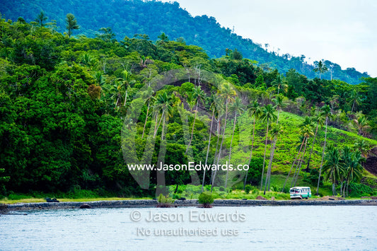 A school bus traveling along a picturesque tropical island road. Natewa Bay, Taveuni Island, Pacific Ocean, Fiji Islands.