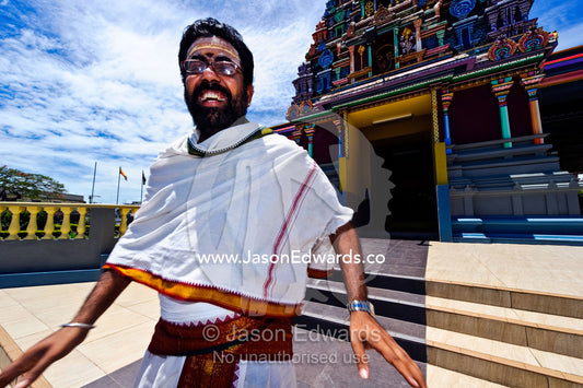 A priest laughing on the steps to a Hindu temple during a festival. Sri Siva Subramaniya Swami Temple, Nadi, Pacific Ocean, Fiji Islands.