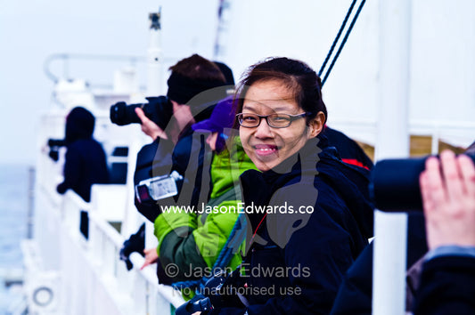 An excited tourist on the windy deck of a ship heading to Antarctica. The Beagle Channel, Tierra del Fuego Archipelago, Strait of Magellan, Ushuaia, Tierra del Fuego Province, Patagonia, Argentina.