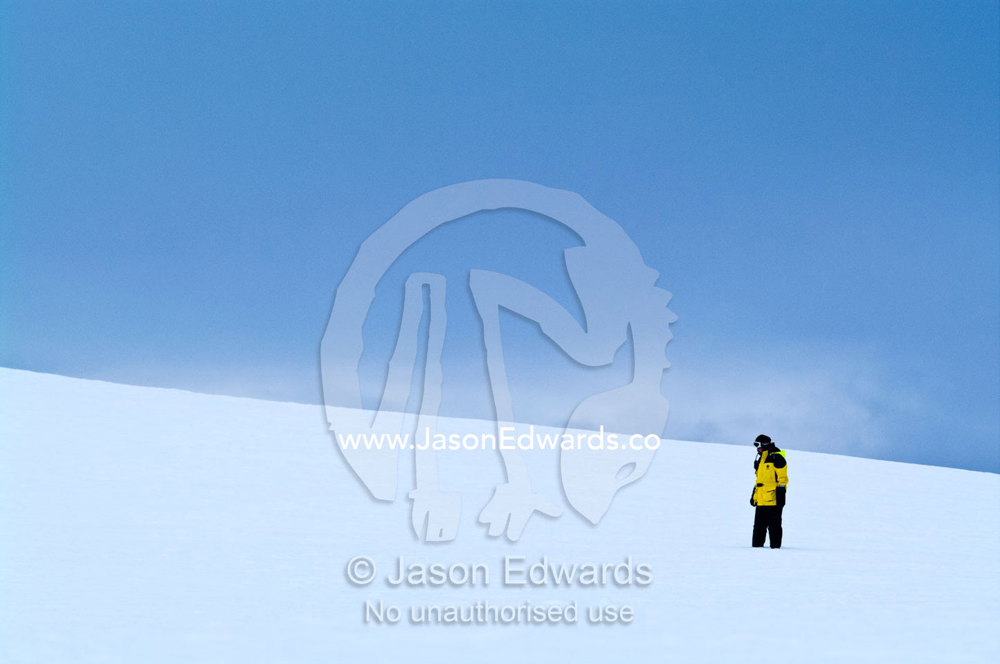 An expedition guide explores a barren ice slope on a rugged island. Prospect Point, Crystal Sound, Antarctic Peninsula, Antarctic Circle, Antarctica.