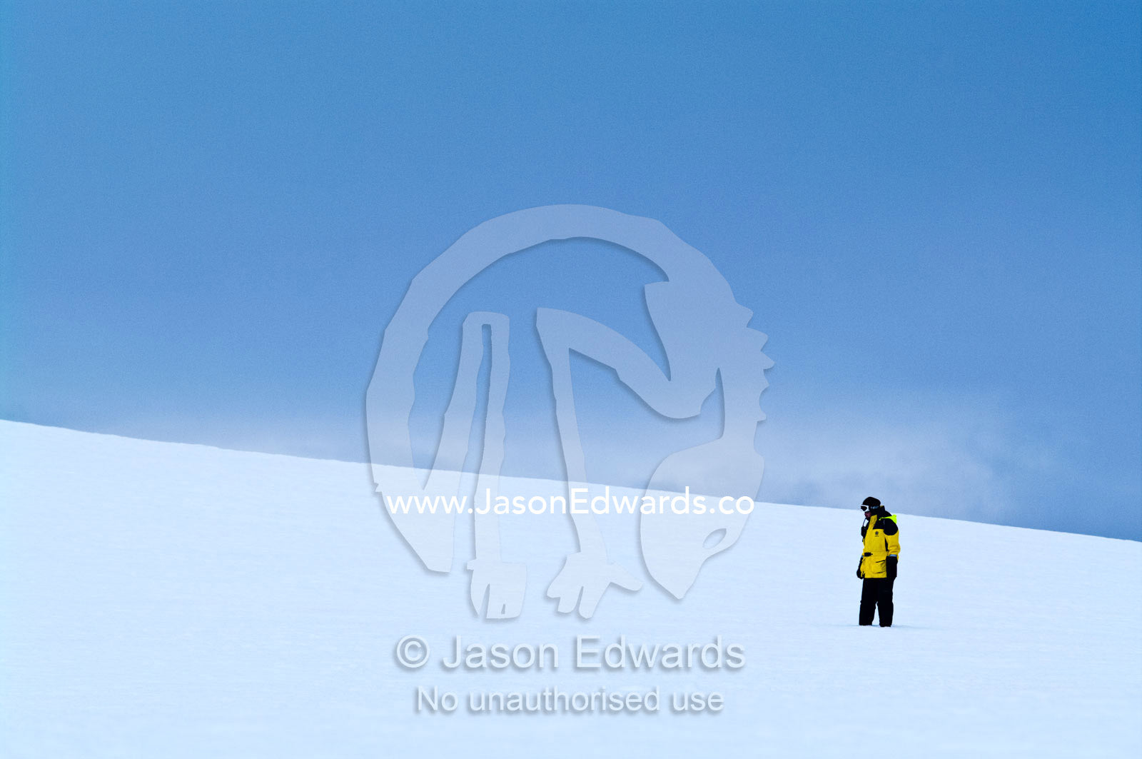 An expedition guide explores a barren ice slope on a rugged island. Prospect Point, Crystal Sound, Antarctic Peninsula, Antarctic Circle, Antarctica.
