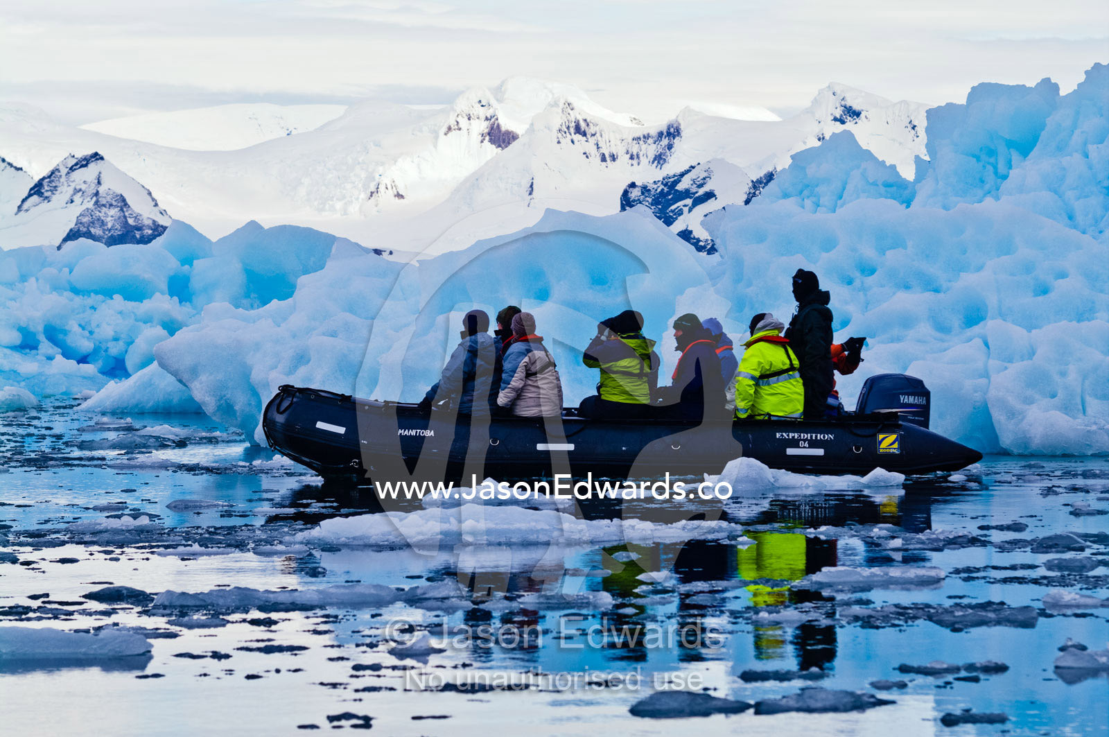 Tourists explore rugged blue icebergs cruising in an inflatable boat. Fish Islands, Flounder Island, The Minnows, Crystal Sound, Antarctic Peninsula, Antarctic Circle, Antarctica.