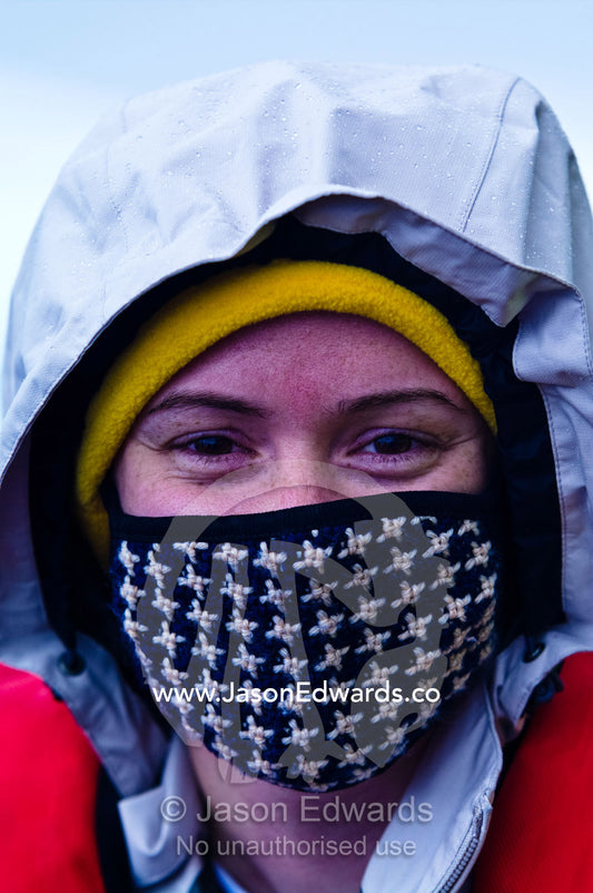 A tourist with a warm woollen mask on her face to fend off icy winds. Fish Islands, Flounder Island, The Minnows, Crystal Sound, Antarctic Peninsula, Antarctic Circle, Antarctica.