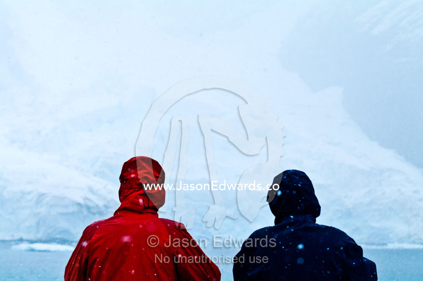 Tourists study the icy shore of an Antarctic island in a blizzard. Pl��neau and Booth Islands, Bellingshausen Sea, Antarctic Peninsula, Antarctica.