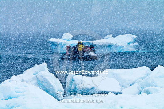 Tourists land on a snow and ice covered island during a blizzard. Danco Island, Antarctic Peninsula, Antarctica.
