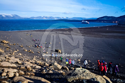 Tourists hike down a volcanic mountainside towards their waiting ship. Whalers Bay, Antarctic Historic Site, Port Foster, Deception Island, South Shetland Islands, Antarctic Peninsula, Antarctica.
