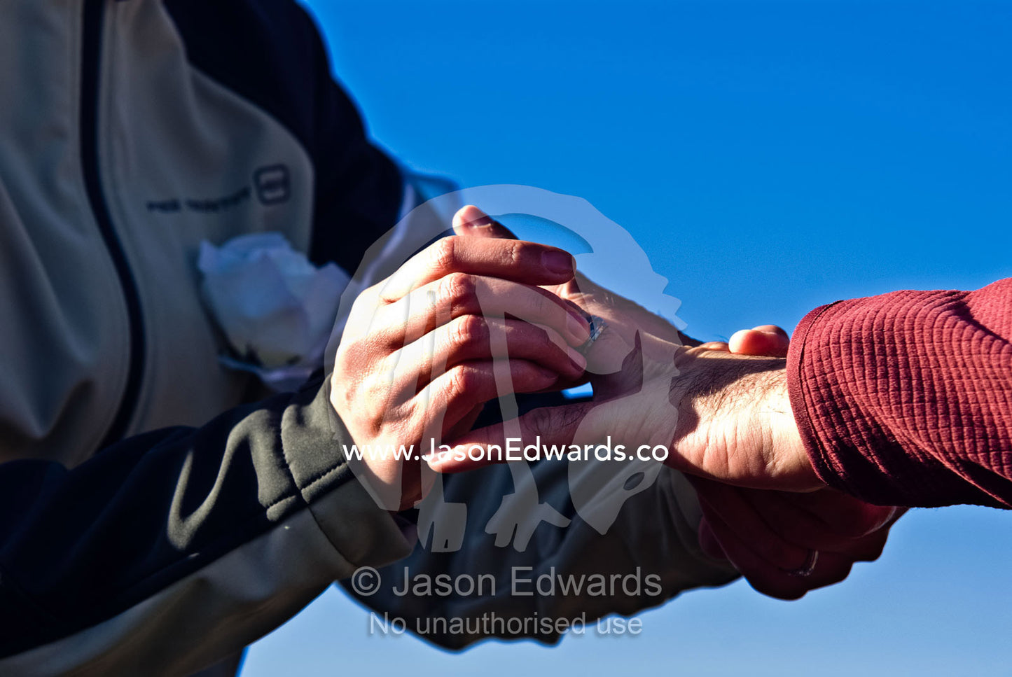 A groom places a wedding band on a finger of his bride in Antarctica. Neptune's Window, Whalers Bay, Antarctic Historic Site, Port Foster, Deception Island, South Shetland Islands, Antarctic Peninsula, Antarctica.