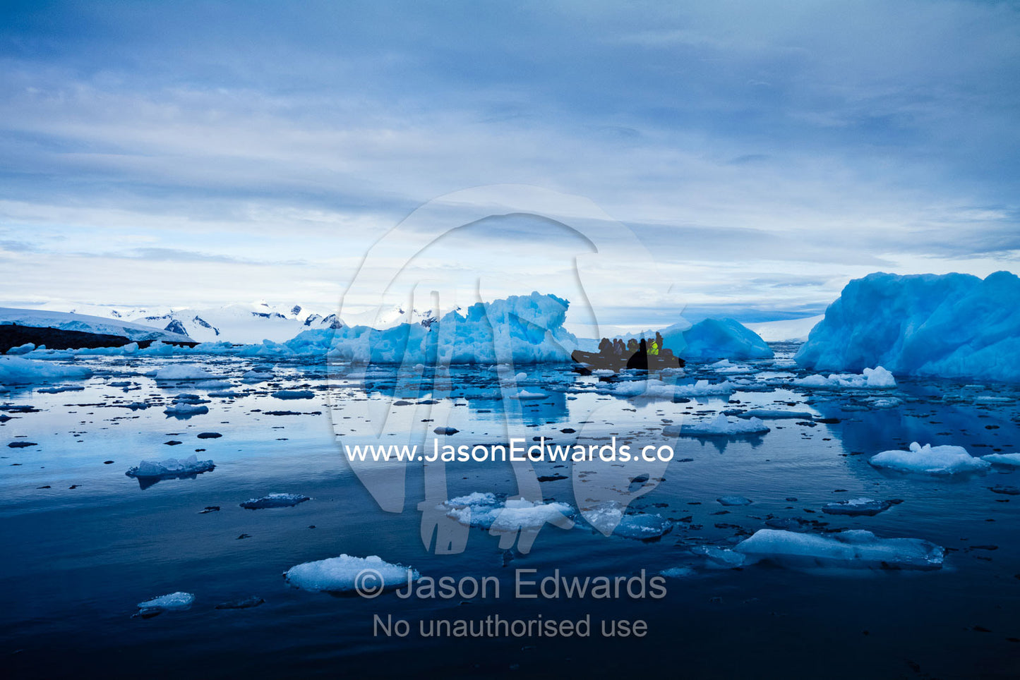 Tourists explore rugged blue icebergs cruising in an inflatable boat. Fish Islands, Flounder Island, The Minnows, Crystal Sound, Antarctic Peninsula, Antarctic Circle, Antarctica.