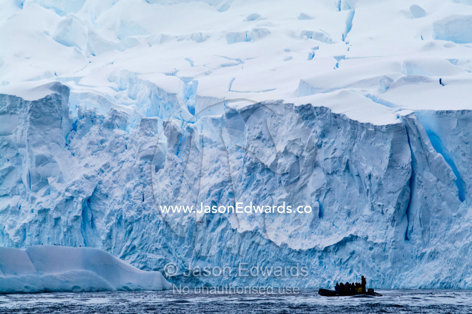 Tourists explore a rugged glacier fracture zone in an inflatable boat. Crystal Sound, Hansen Island, Hanusse Bay, Antarctic Peninsula, Antarctic Circle, Antarctica.