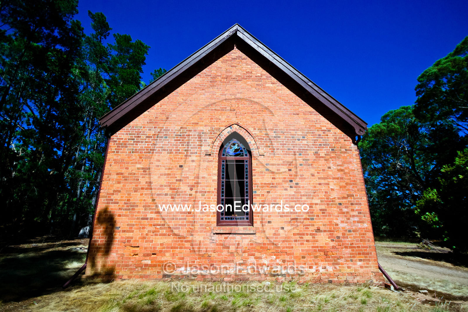 A stain glass window in a small country church made of red bricks. Elphinstone, Victoria, Australia.