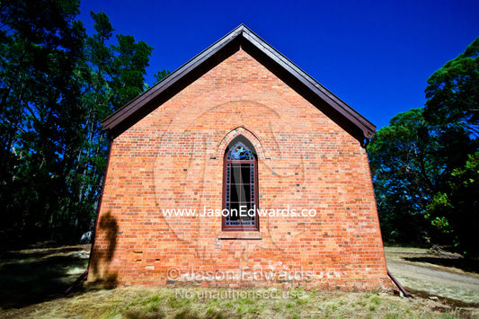 A stain glass window in a small country church made of red bricks. Elphinstone, Victoria, Australia.