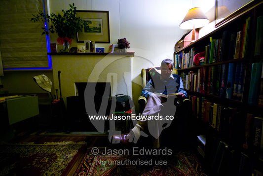 An elderly man reading a book by lamplight in his country home. Castlemaine, Victoria, Australia.