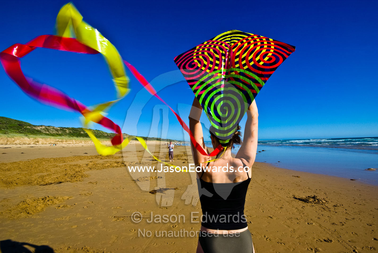 A woman prepares to launch a kite on a windswept beach during summer. Cape Liptrap Coastal Park, Venus Bay, Bass Strait, South Gippsland, Victoria, Australia.