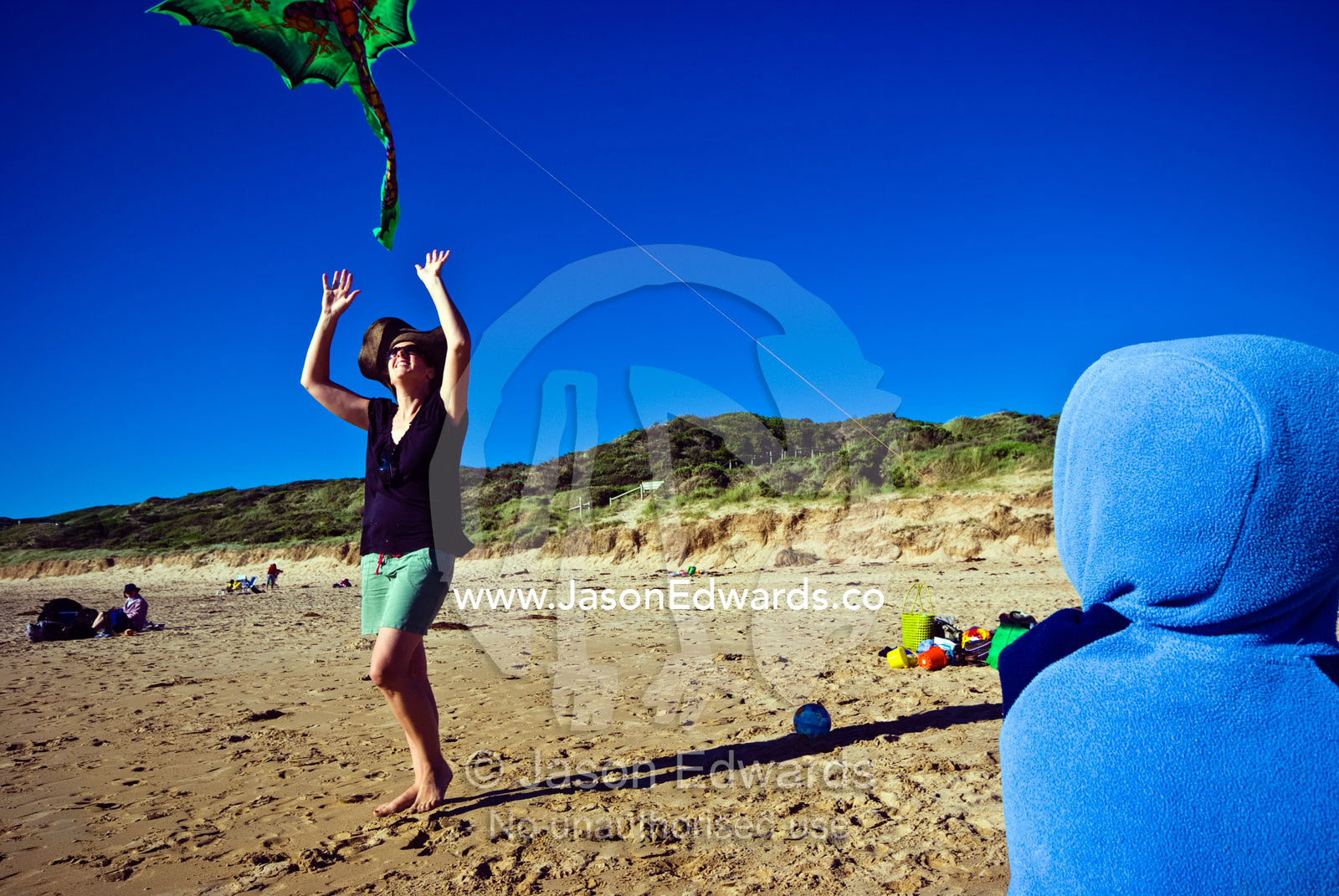 A mother launches a kite for her small son on a windy beach in summer. Cape Liptrap Coastal Park, Venus Bay, Bass Strait, South Gippsland, Victoria, Australia.