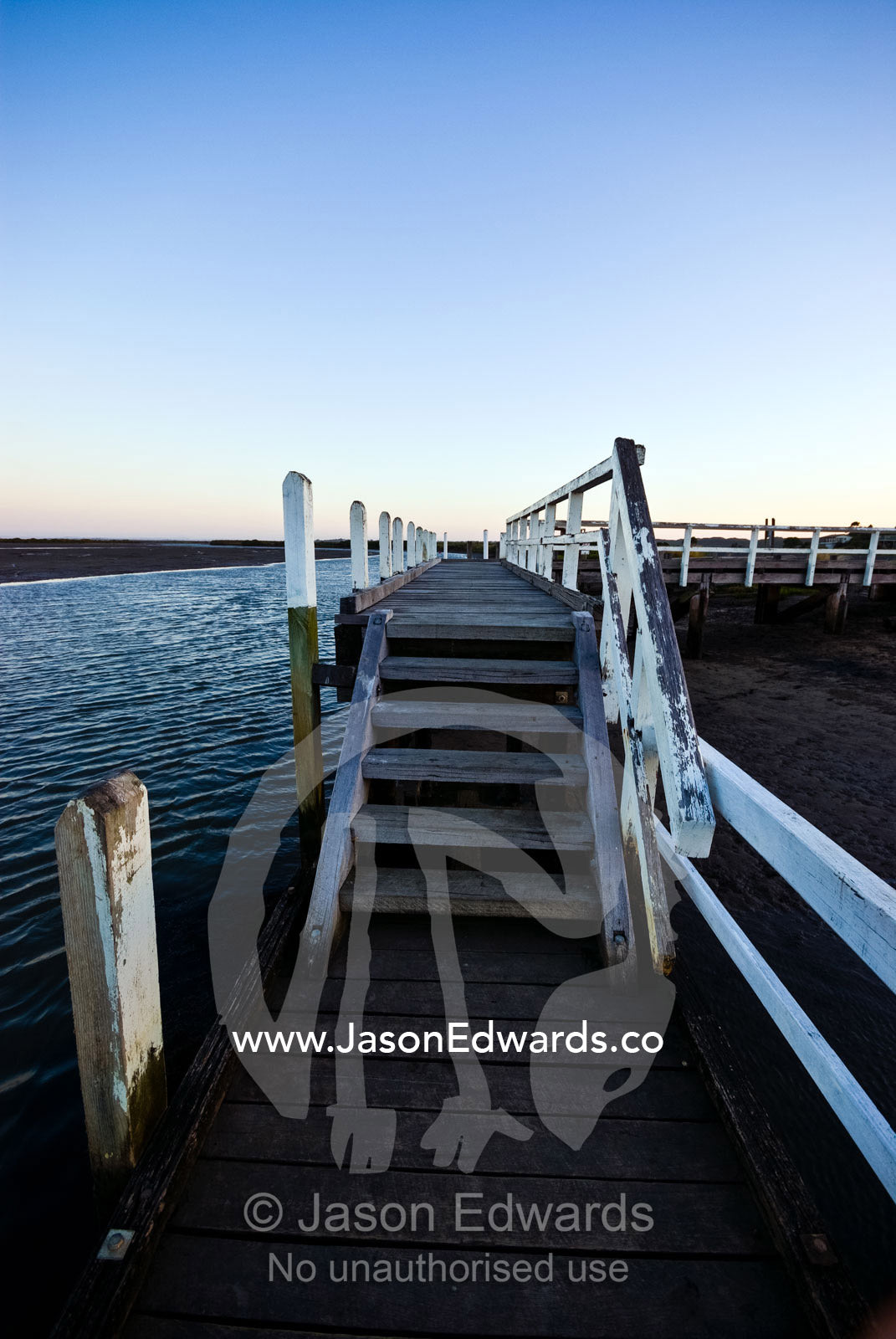Twilight descends over jetty above a wide tidal river and mud flat. Anderson's Inlet, Venus Bay, South Gippsland, Victoria, Australia.