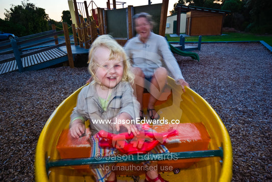 A young boy plays in a rocking boat in a children's playground. Anderson's Inlet, Venus Bay, South Gippsland, Victoria, Australia.