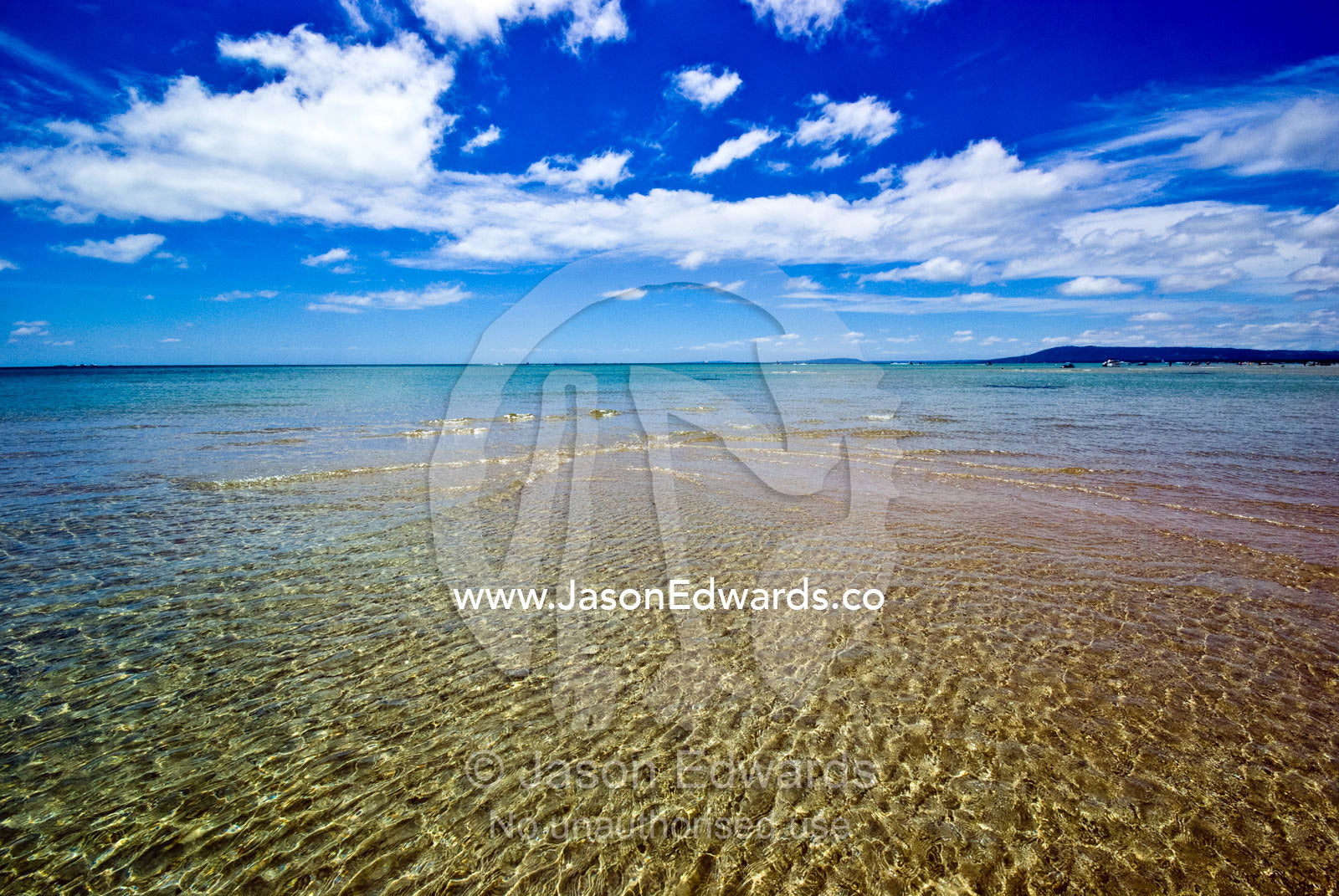 Tiny waves lap over a sand bar at low tide on a bright summers day. Rye Beach, Melbourne, Victoria, Australia.