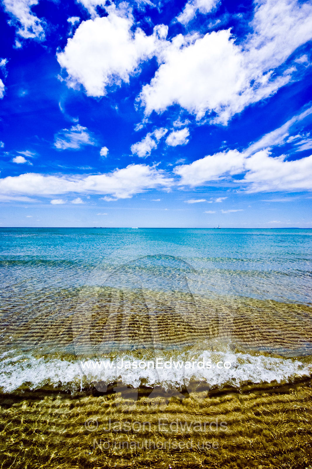 Tiny waves lap over a sand bar at low tide on a bright summers day. Rye Beach, Melbourne, Victoria, Australia.