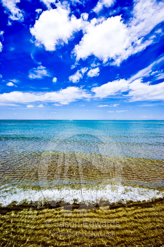 Tiny waves lap over a sand bar at low tide on a bright summers day. Rye Beach, Melbourne, Victoria, Australia.