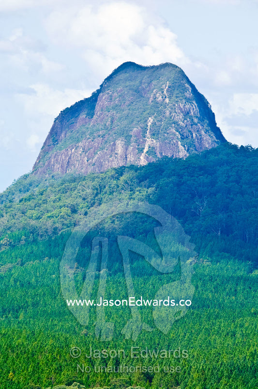 An eroded ancient volcanic plug rises above a forested plain. Mount Tibrogargen, Glass House Mountains, Brisbane, Queensland, Australia.