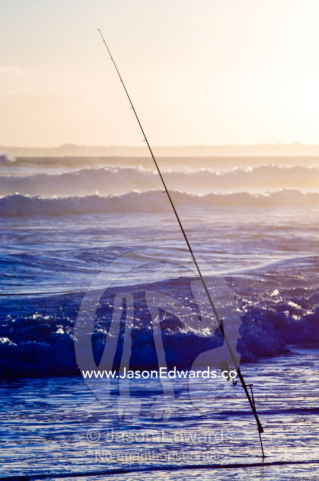 A surf fishing rod and reel in the shallows waiting to hook a fish. Venus Bay, Bass Strait, South Gippsland, Victoria, Australia.