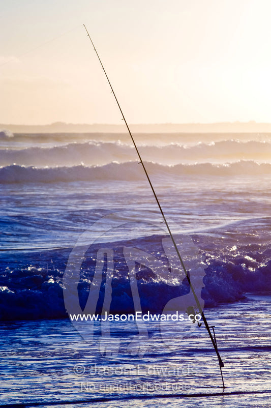 A surf fishing rod and reel in the shallows waiting to hook a fish. Venus Bay, Bass Strait, South Gippsland, Victoria, Australia.