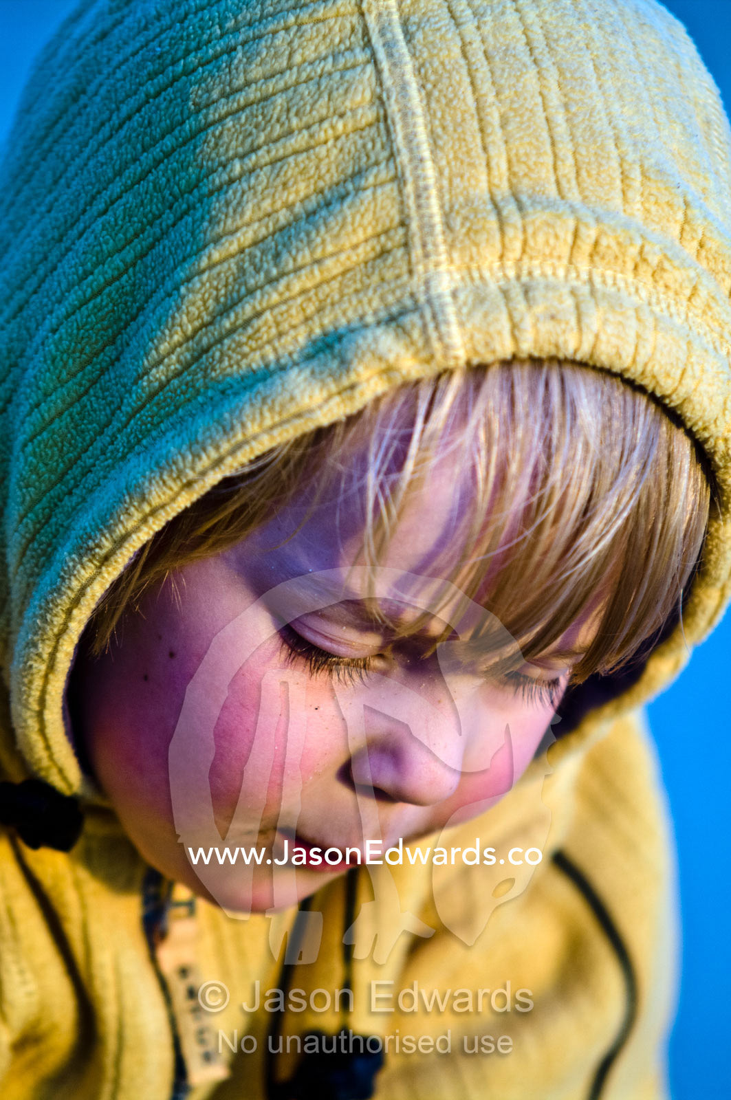 A boy rugged up in a hood on a beach concentrating on his sand castle. Venus Bay, Bass Strait, South Gippsland, Victoria, Australia.